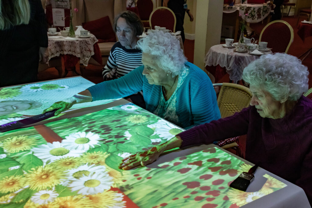 Image shows older people using projector games on a table